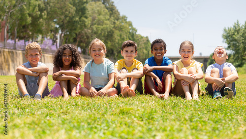 Happy children sitting on the green grass on a sunny day