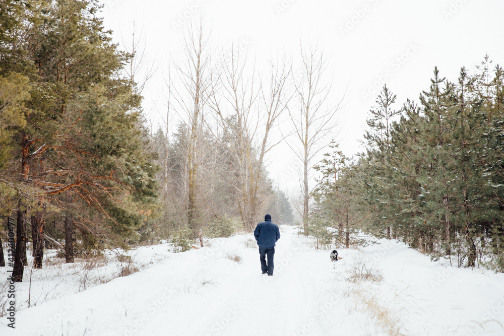 Man walking with dog at winter forest Man walking with dog at winter forest
