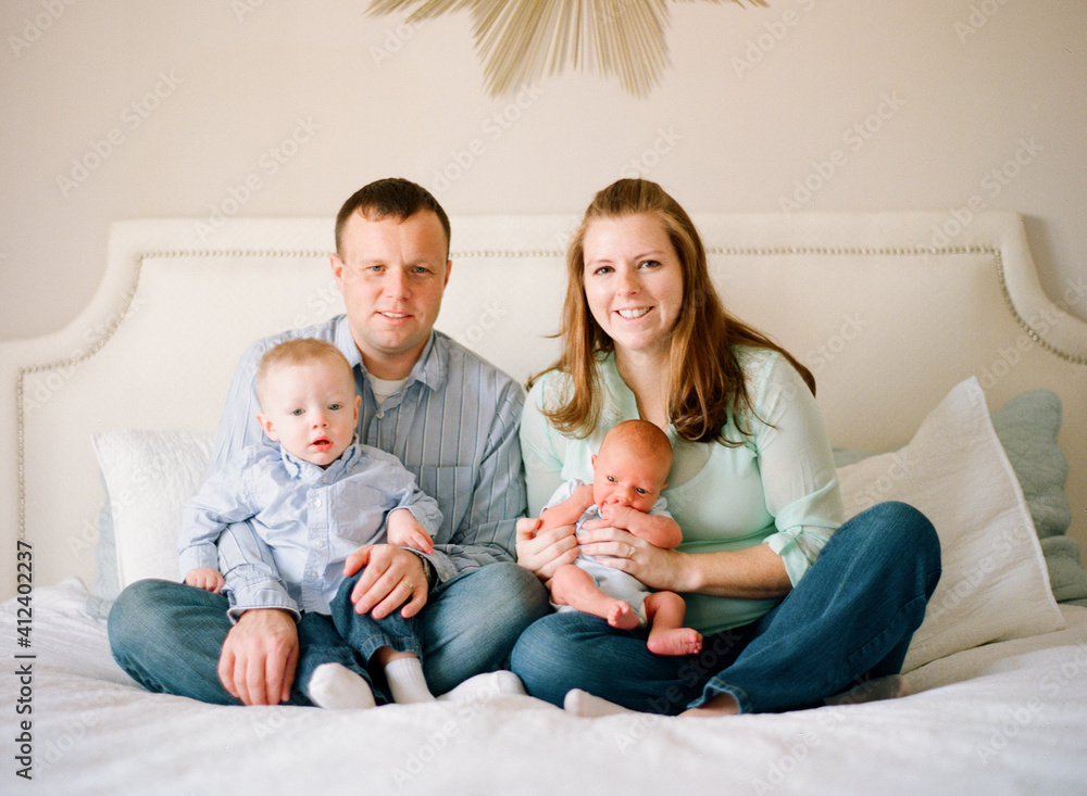 New family sitting on the bed smiling with their new baby New family sitting on the bed smiling with their new baby