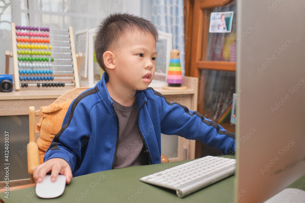 Cute little Asian kid with personal computer making video call at home, Kindergarten boy concentrate on studying online, attending school via e-learning, Child at home, Distance Learning concept Cute little Asian kid with personal computer making video call at home, Kindergarten boy concentrate on studying online, attending school via e-learning, Child at home, Distance Learning concept