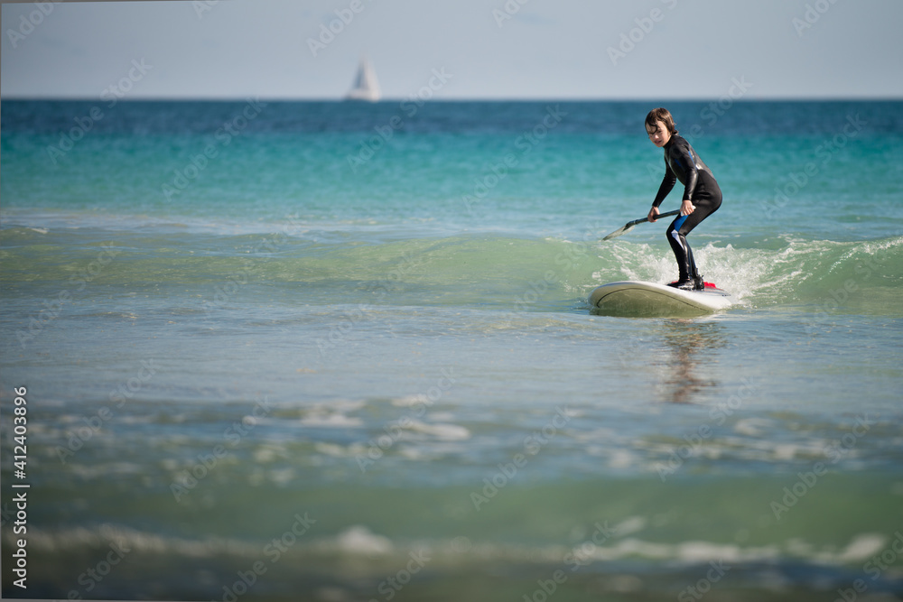 Young boy catching a wave on a stand up paddle board Young boy catching a wave on a stand up paddle board