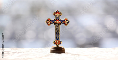 A strong powerful image of a detailed crucifix ornament on a lightly patterned satin sheet with a plain heavily blurred bokeh background much like a landscape composition © LincB