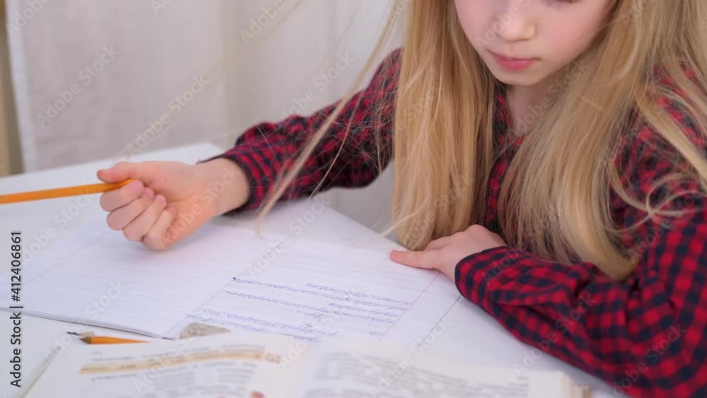 4k Blonde schoolgirl studying at home doing school homework. Training books and notebooks on table. Distance learning online education 4k Blonde schoolgirl studying at home doing school homework. Training books and notebooks on table. Distance learning online education