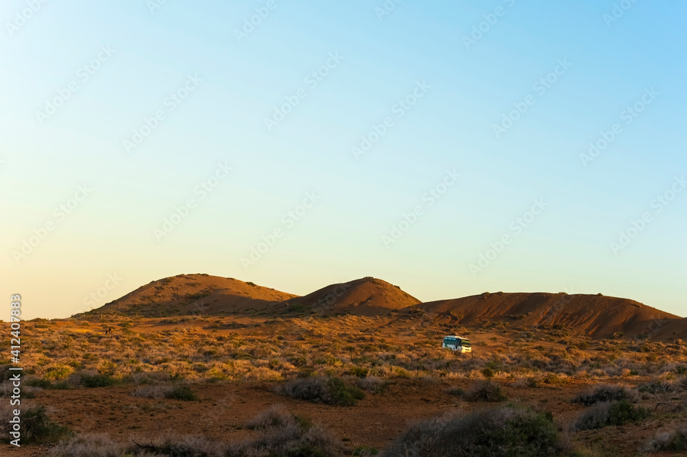 Van crossing a desert landscape at sunset