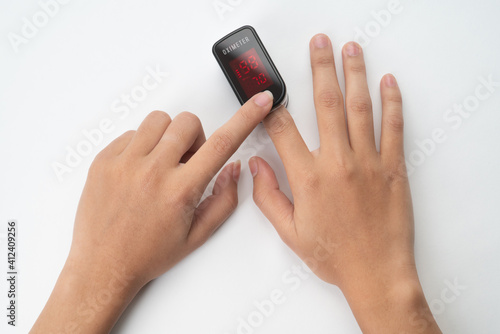 Top view of Pulse Oximeter, finger digital device to measure person's oxygen saturation. Reduced oxygenation is an emergency sign of pneumonia caused by flu or novel coronavirus. Device on Fingertip (ID: 412409256)