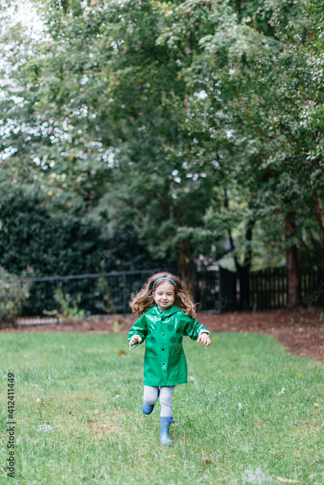 Cute young girl running in a raincoat outside Cute young girl running in a raincoat outside