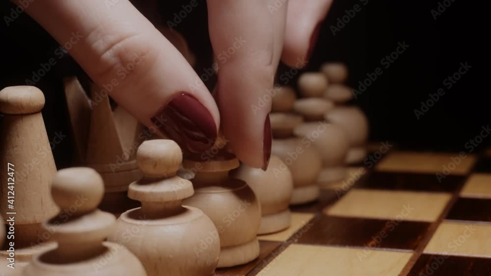 Classy lady making a first move in chess. Starting a game, woman leadership concept. Close up of a girl's hand with red nails, opening gambit. Classy lady making a first move in chess. Starting a game, woman leadership concept. Close up of a girl's hand with red nails, opening gambit.
