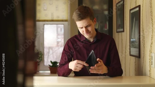 Dissapointed Young buisnessman checking empty wallet. Person looks into the wallet with no money in it.