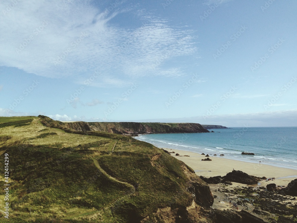 A cliff-top coast path and beach. A cliff-top coast path and beach.