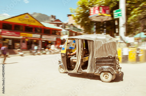 A motorised tuk-tuk travelling through an Indian village photo