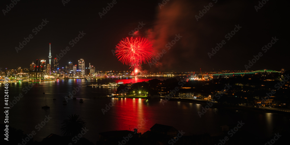 Auckland dazzled by fireworks display with Sky Tower on the left side and Harbour bridge illuminated on the right side. Taken at North Head, Devonport, Auckland