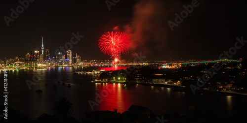Auckland dazzled by fireworks display with Sky Tower on the left side and Harbour bridge illuminated on the right side. Taken at North Head  Devonport  Auckland