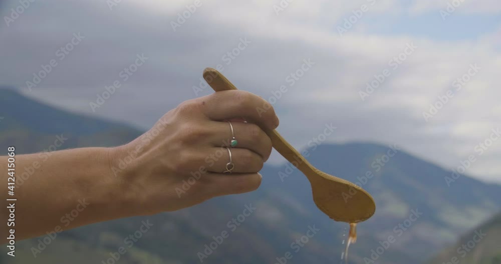 Hand of woman who dipped a wooden spoon into a vessel with yellow liquid. Close up of woman hands with spoon and yellow liquid Hand of woman who dipped a wooden spoon into a vessel with yellow liquid. Close up of woman hands with spoon and yellow liquid