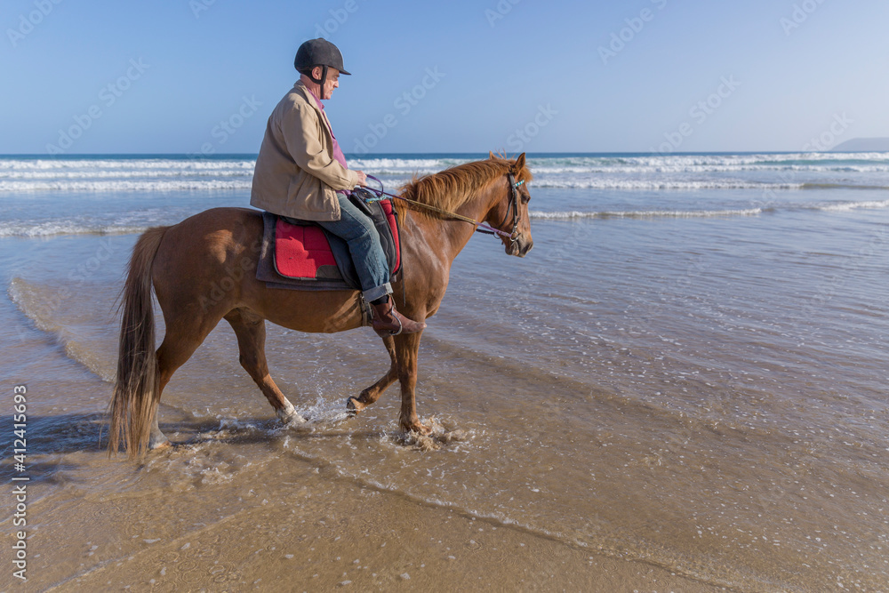 Profile of senior male riding horseback in shorebreak Profile of senior male riding horseback in shorebreak