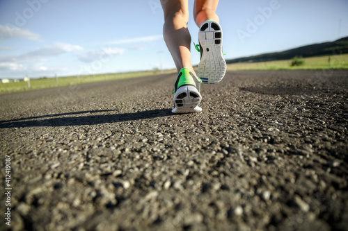 a close up of running shoes running away from camera down a paved road