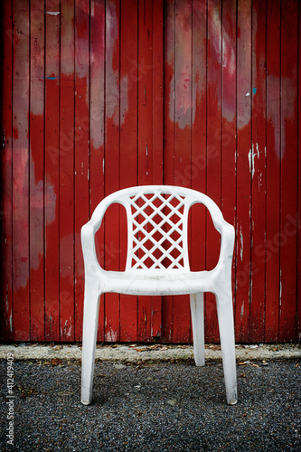 A three legged white plastic chair photo