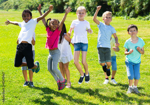 Happy school children jumping on the green lawn. High quality photo