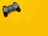 Black joystick gaming controller on trendy yellow background with space for text: video game console concept for Interactive Entertainment gamer 