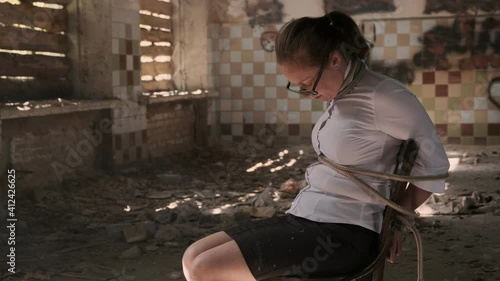 Exhausted woman victim of abduction in abandoned building with bowed head.