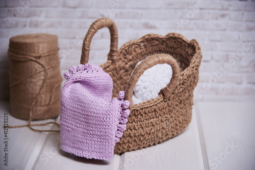 handmade knitted basket on a wooden table. Next to the thread in the skeins for yarn. Cozy arrangement of the house made of ecological materials