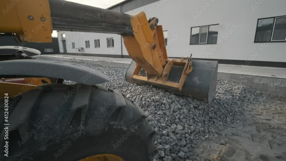 Tractor moves rubble to truck. Excavator-loader rakes rubble from pile ...