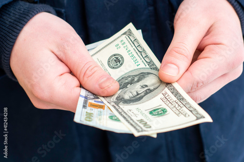 a man holds two hundred-dollar bills in his hands close-up