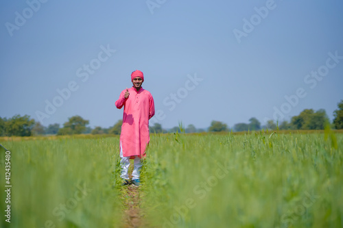 Young indian farmer standing his wheat field and giving happy expression © PRASANNAPIX