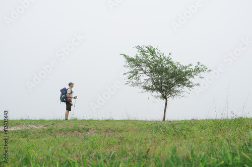 A Chinese young man hiking on grassland and looking at a tree,Beijing,China photo