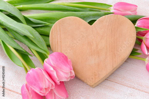 Beautiful flowers and wooden heart on light background