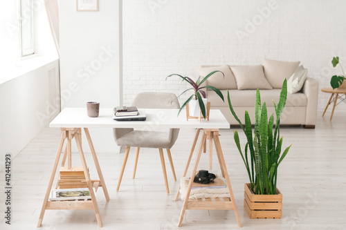 Modern work place in living room or studio, natural light, home plants