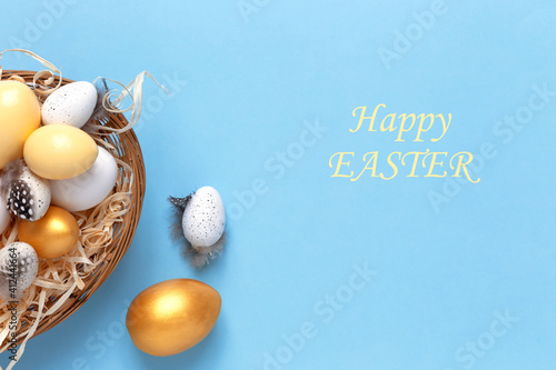 Easter background with colorful eggs in a basket on a blue background. Top view with copy space