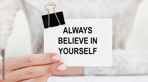 Konstfotografi The girl holds in front of her a card with the text Always believe in yourself
