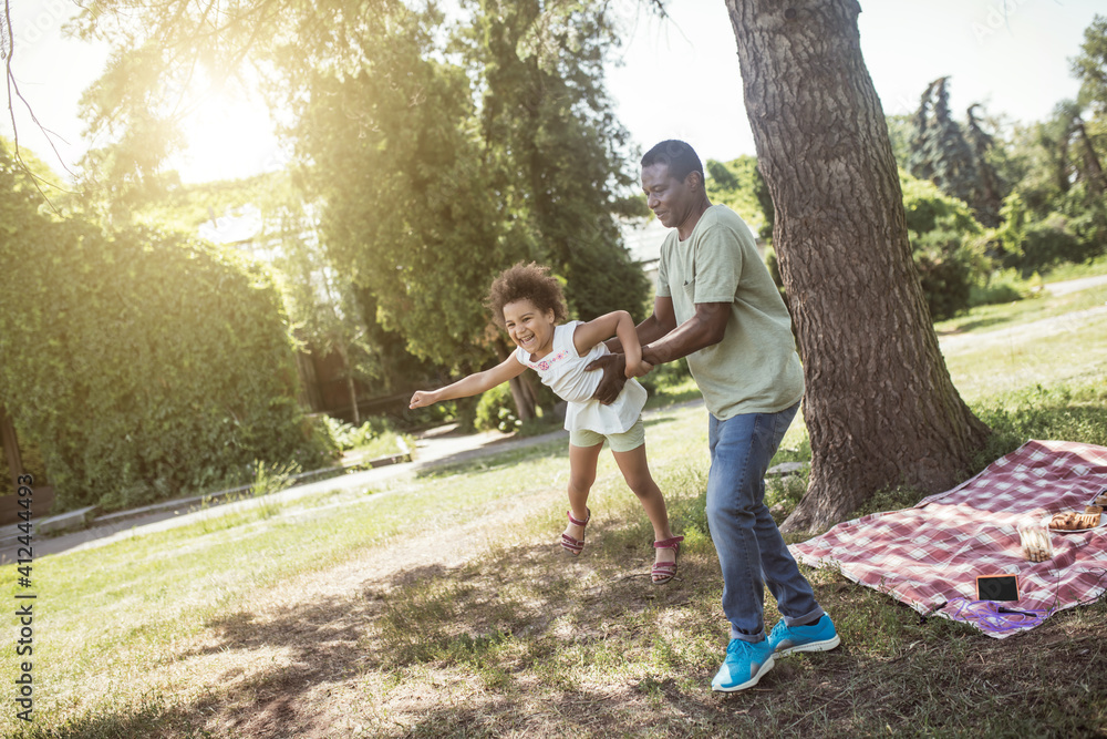 African american dad and his daughter having good time together in the park and feeling playful