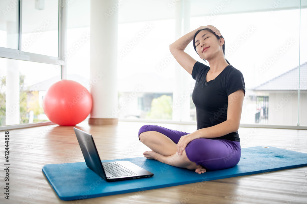 Fit woman doing yoga and watching online tutorials on notebook Fit woman doing yoga and watching online tutorials on notebook