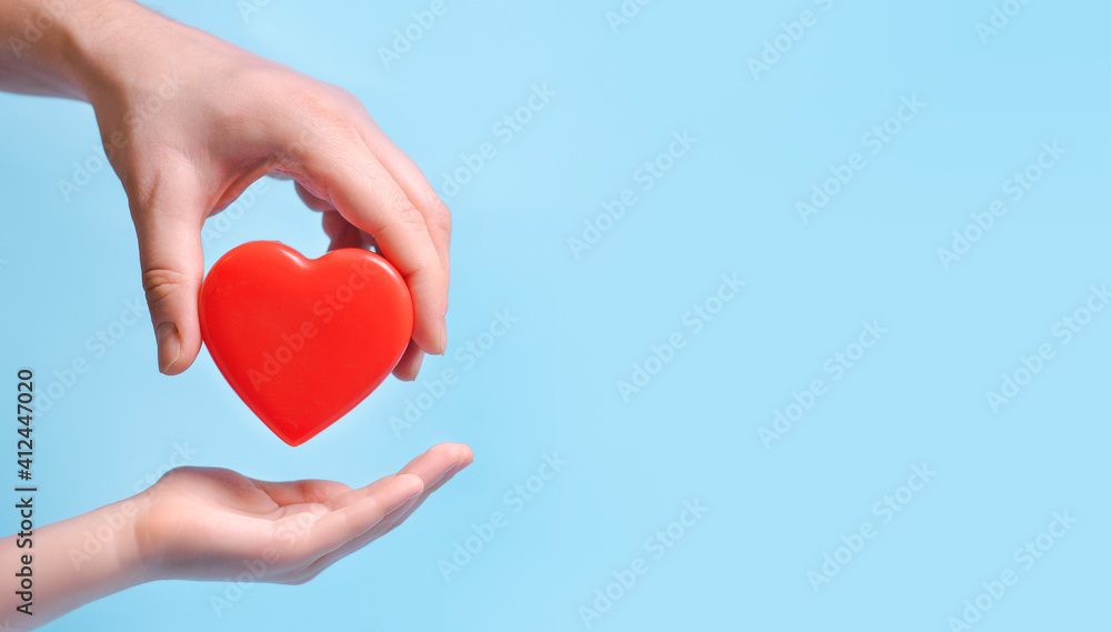 Hand person giving a heart to another person on blue background.Poster, copy space for text Hand person giving a heart to another person on blue background.Poster, copy space for text
