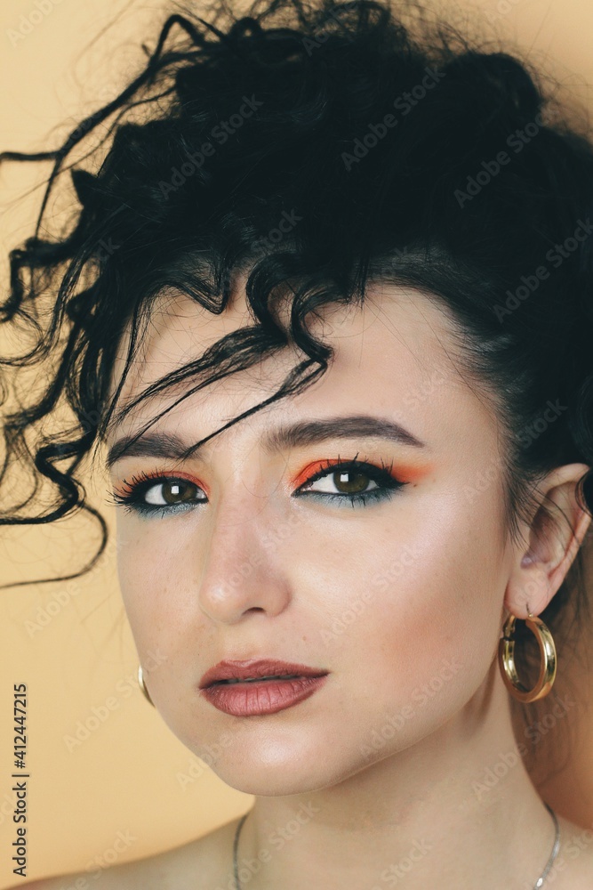 Beautiful young brunette model with bright make-up and curly hairstyle