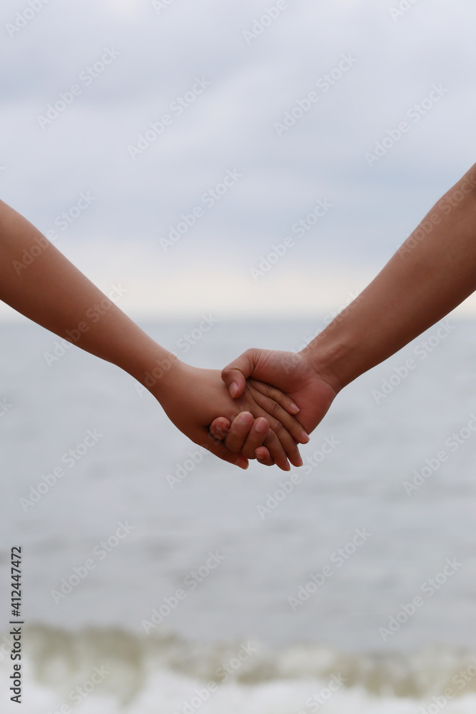 Young people holding hands on calm sea background.