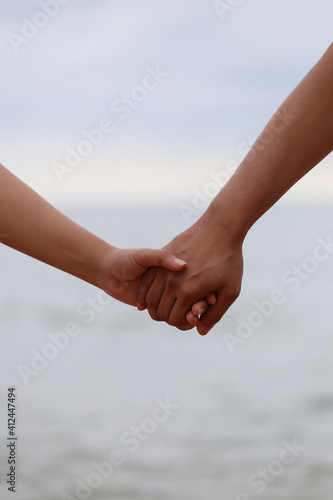 Young people holding hands on calm sea background. © meepoohyaphoto