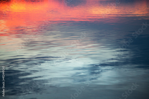 Background with reflection of the sunset on the sea surface. Abstract reflection of the sky in the blurred background of water
