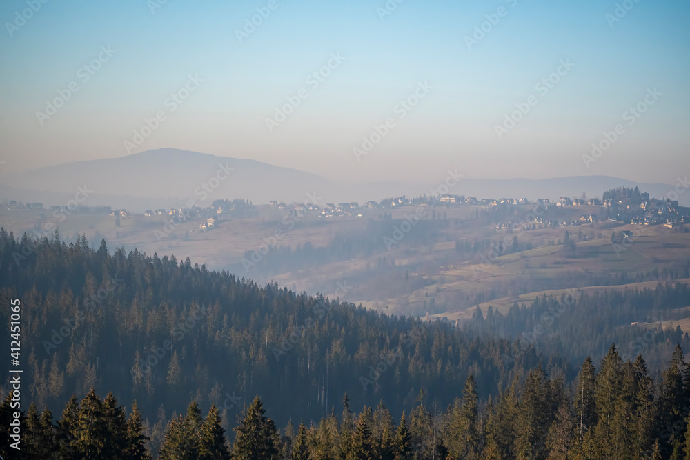 Babia Góra Mount seen from Bukowina Tatrzańska, Poland. Smog is covering the hills and filling cold winter air. Selective focus on the forest, blurred background.