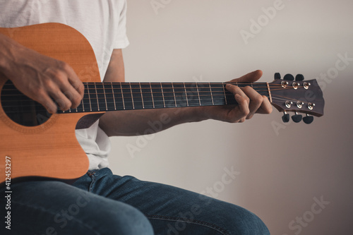 Closeup of hands working on an instrumental instrument while playing and singing at home due to quarantine. The sitting singer strums the guitar. To improve your mood