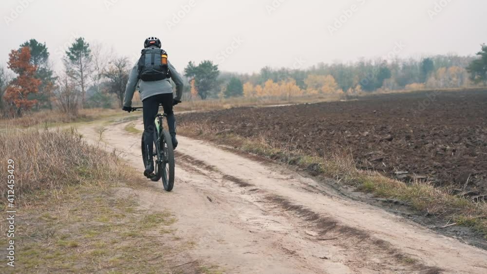 Athlete man riding a mountain bike down a road in the countryside Athlete man riding a mountain bike down a road in the countryside