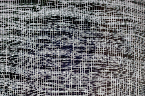 Textured background of the old shabby fabric, gauze. White uneven lines on a black background creating a grid pattern