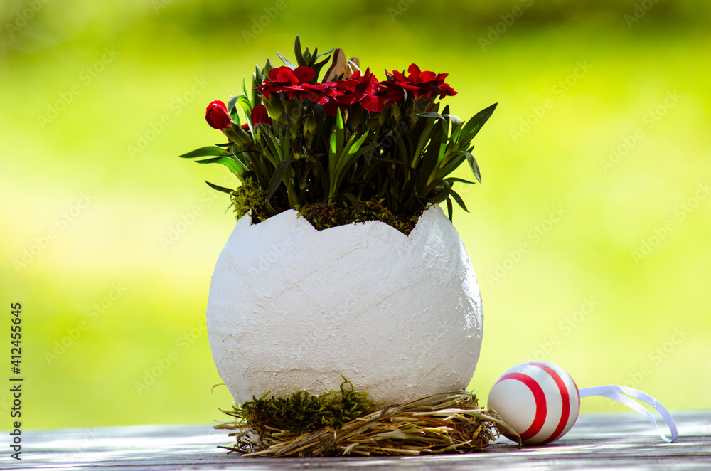 Easter egg as a flower vase in front of a blurred background and a decorative egg