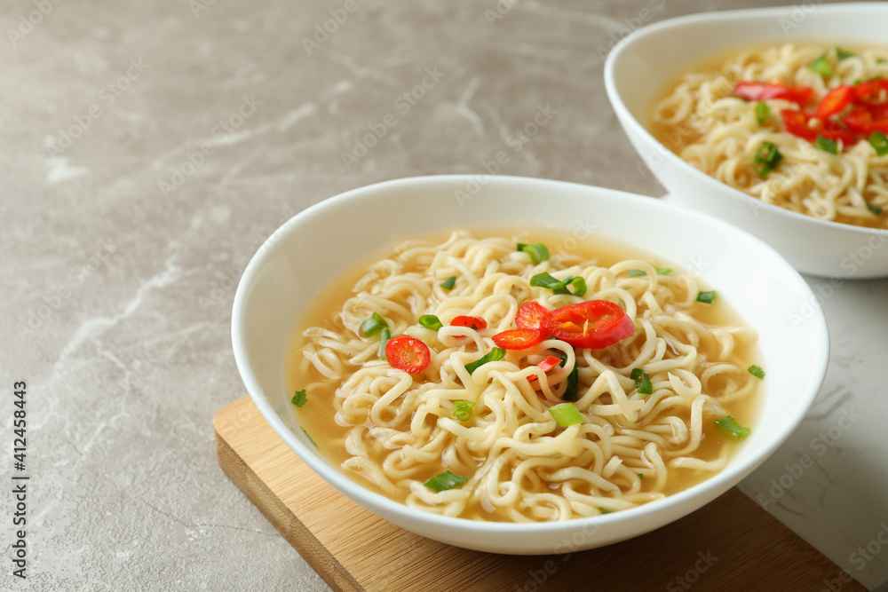 Concept of tasty eating with bowls of noodles on gray background