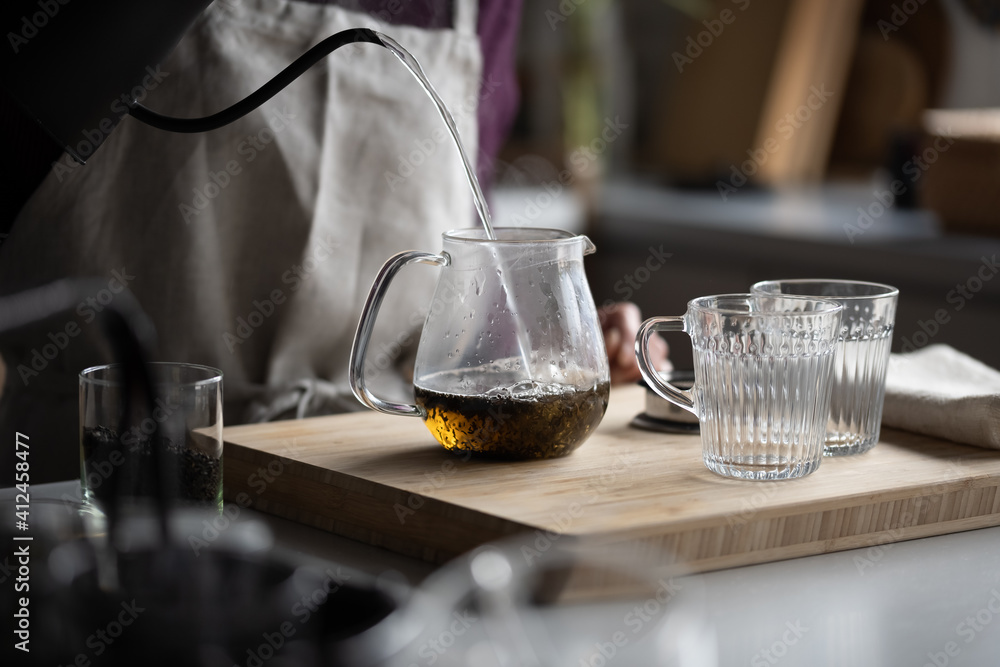 Woman is making hot tea in the kitchen. Woman is making hot tea in the kitchen.