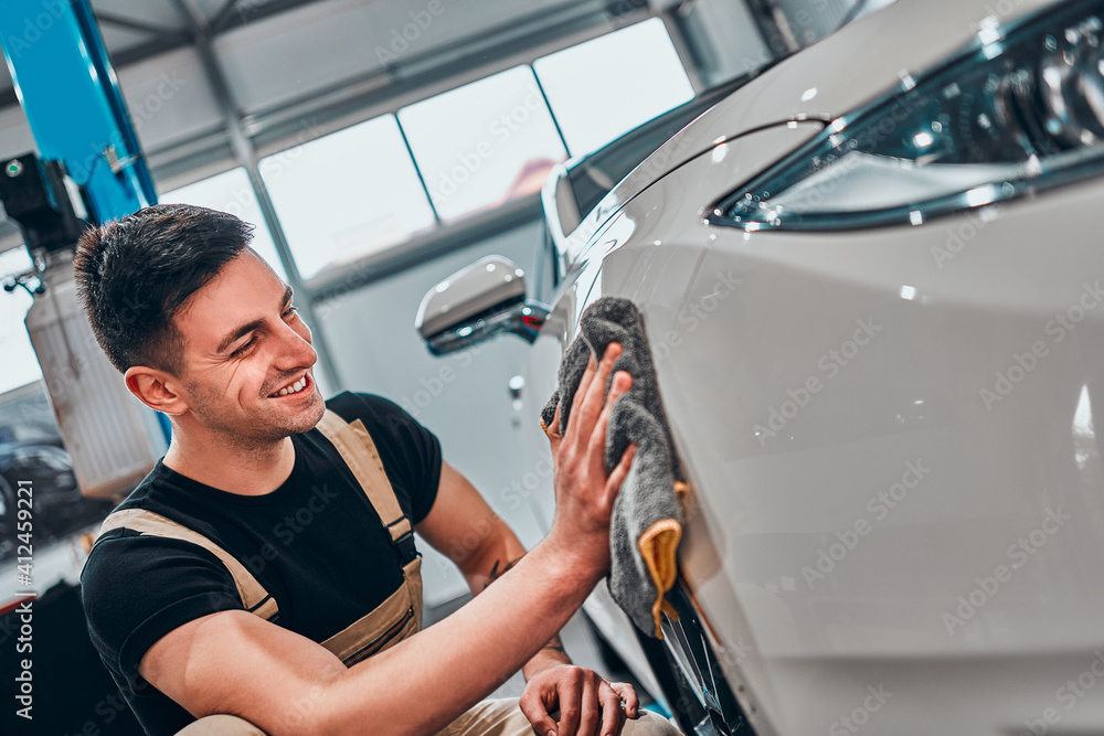 Car detailing. The man holds the microfiber in hand and polishes the car. Car detailing. The man holds the microfiber in hand and polishes the car.
