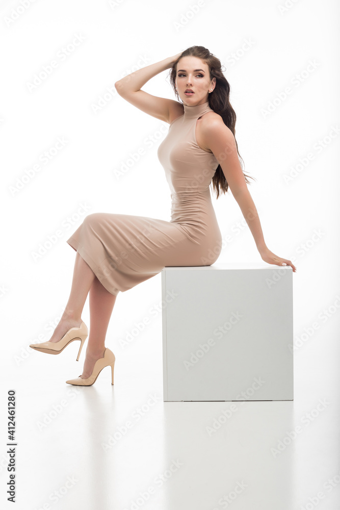 beautiful fashionable young girl in a beige dress posing on a white background