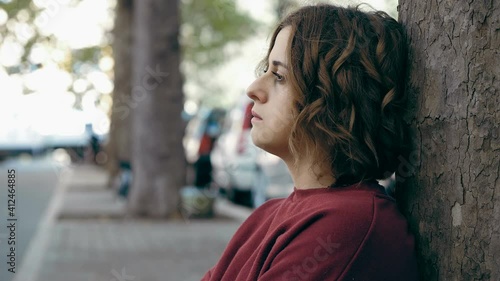 depression, sadness - sad girl leaning against a tree lokks away thinking photo