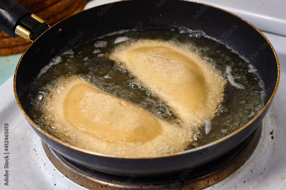 Process with fried in sunflower oilof homemade qutab or chebureki, calzone with minced meat and onion. Process of making food at the kitchen. Azerbaijani, Tatar, Caucasian, Greek cuisine. Process with fried in sunflower oilof homemade qutab or chebureki, calzone with minced meat and onion. Process of making food at the kitchen. Azerbaijani, Tatar, Caucasian, Greek cuisine.